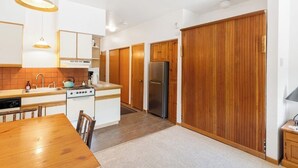 Eine moderne Küche mit weißen Schränken, einem Holzespeisesaal und einer großen Holztür zum Verschieben.