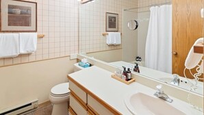 Ein Badezimmer mit Waschtisch, Waschbecken, Spiegel und Handtuchhalter.