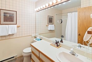 Ein Badezimmer mit Waschtisch, Waschbecken, Spiegel und Handtuchhalter.