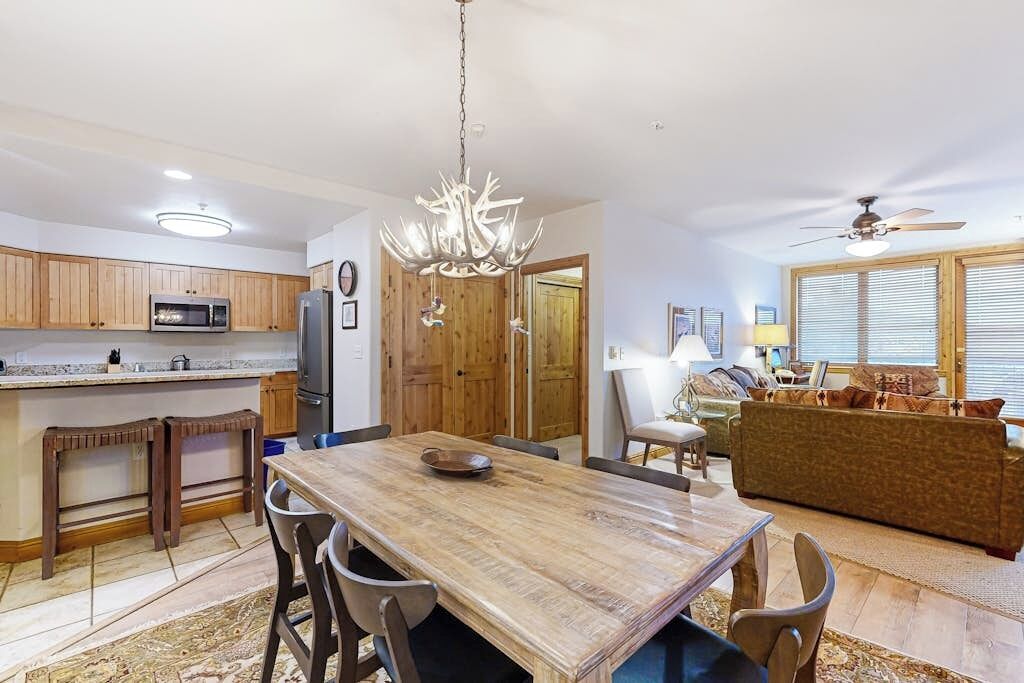 A spacious kitchen with wooden cabinets, a dining table, and a chandelier.