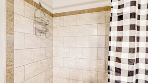 A bathroom with beige tiles, a checkered shower curtain, and a towel rack. - Base area studio w/shared pool & hot tub, private balcony - steps from ski lifts (Steamboat Springs)