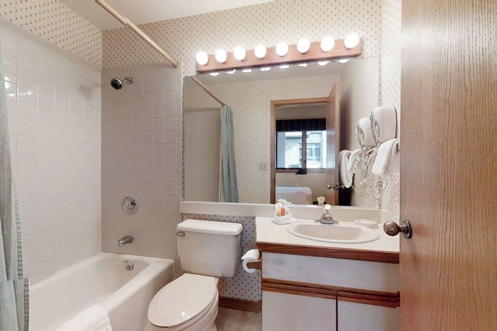 A bathroom with a bathtub, toilet, vanity with a mirror, and a shower area.