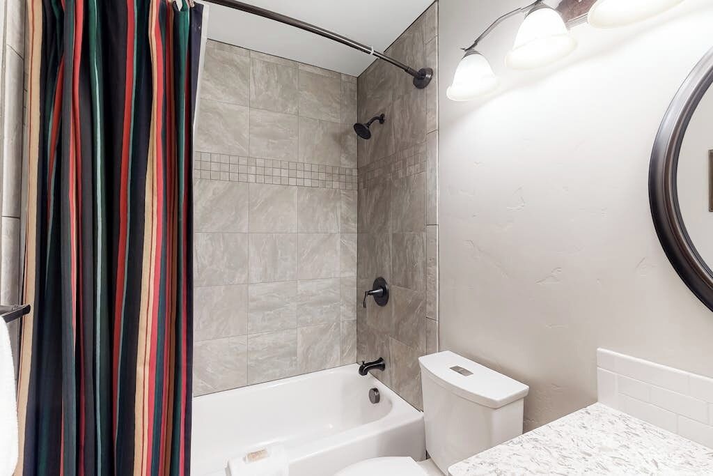 A bathroom with a bathtub, toilet, and a shower curtain.