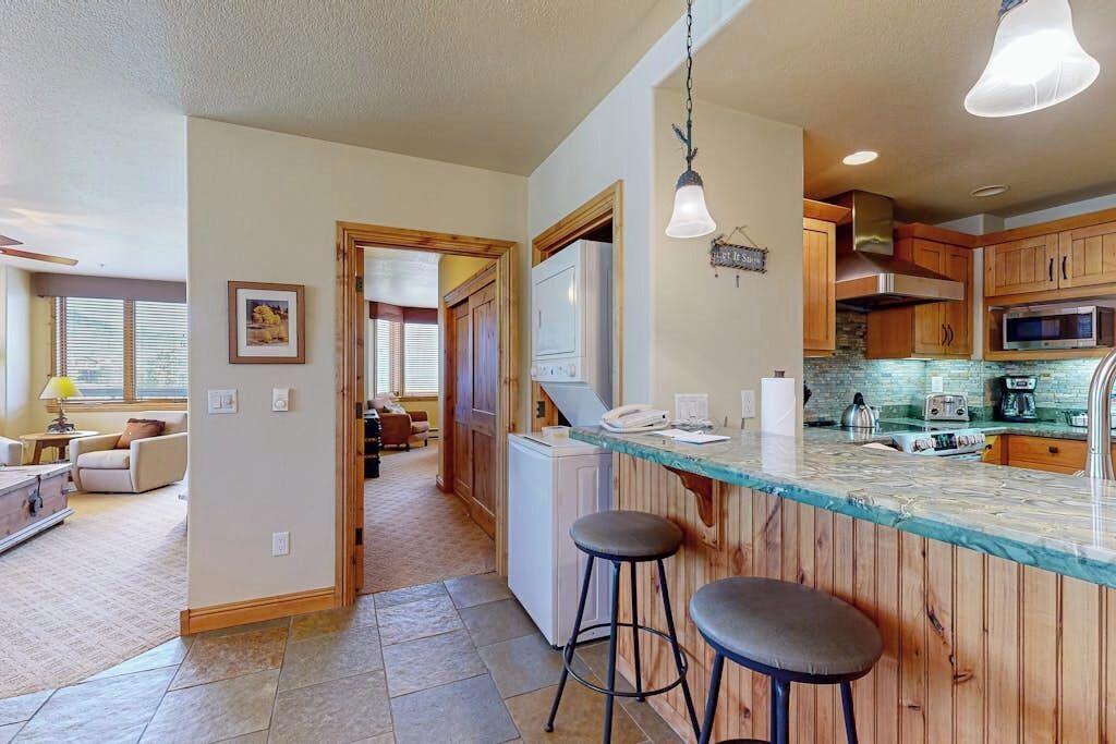 A kitchen with wooden cabinets, a marble countertop, and two bar stools.