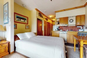Ein Schlafzimmer mit einem Bett, einer kleinen Küchenzeile mit Herd und Holzschränken.