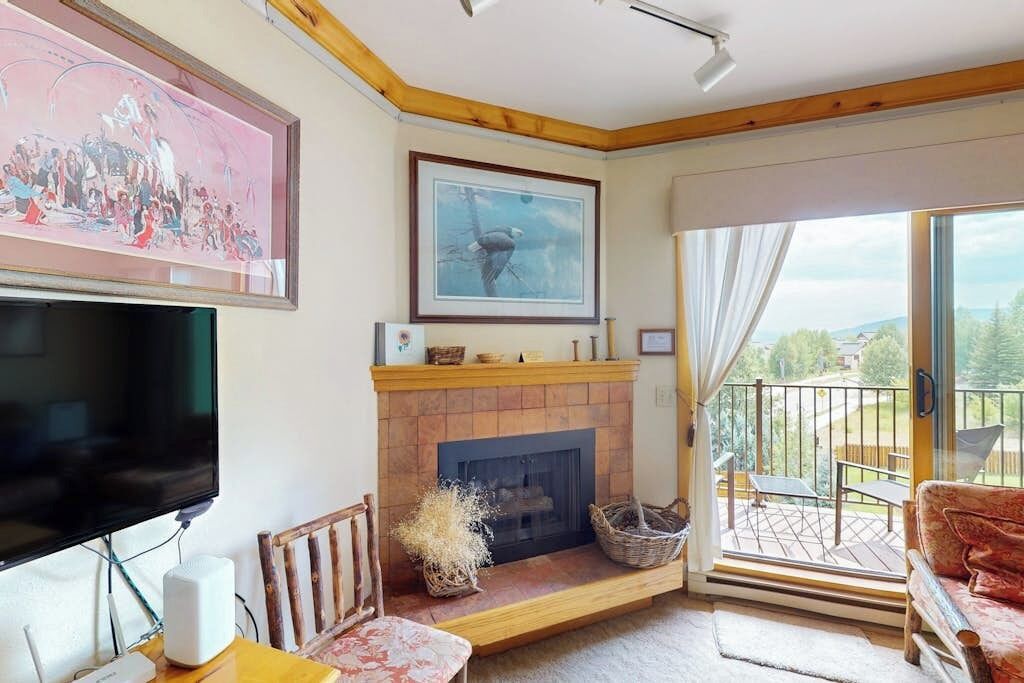 Un salon avec une cheminée, un téléviseur et un balcon offrant une vue agréable.