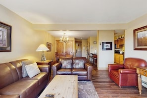 A living room with a brown leather sofa, a wooden coffee table, and a red leather armchair. - Warm & inviting condo with sauna, pool & hot tubs (Steamboat Springs)