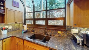 A kitchen with a large window, wooden cabinets, and a tiled backsplash. - Modern Frisco Townhome with upscale features & world-class skiing (Frisco)