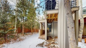 A two-story building with a balcony, a covered porch, and a snow-covered ground. - Modern Frisco Townhome with upscale features & world-class skiing (Frisco)