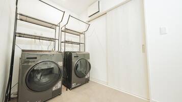 A laundry room with two front-loading washers and dryers, a white wall, and a door.