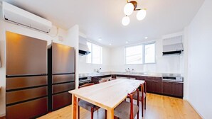 Eine moderne Küche mit Holztisch, integrierten Geräten und großen Fenstern.
