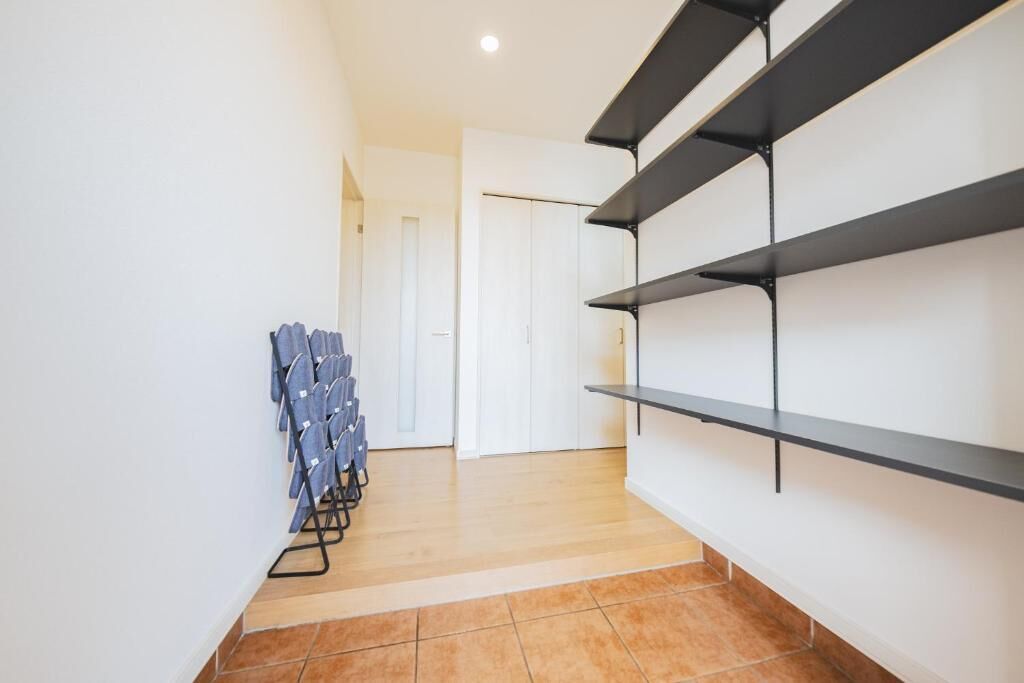 A hallway with a staircase, a door, and a rack of folded chairs.