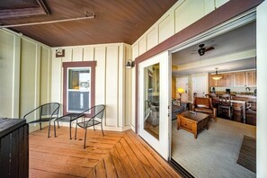 Ein Zimmer mit Holzboden, einer Schiebetür zu einer Küche und einem Essbereich mit Tisch und Stühlen.