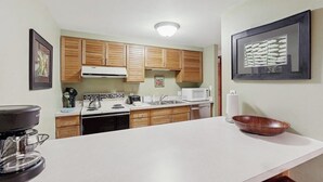 A kitchen with wooden cabinets, a microwave, a coffee maker, and a framed picture on the wall. - Timber Run 416 - Appealing condo with sauna, pool, hot tubs & barbecue area (Steamboat Springs)