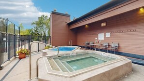 A rooftop pool area with a hot tub, seating, and a fenced patio. - Timber Run 416 - Appealing condo with sauna, pool, hot tubs & barbecue area (Steamboat Springs)