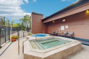 Ein Poolbereich auf dem Dach mit Whirlpool, Sitzgelegenheiten und einer umzäunten Terrasse.