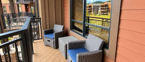 Un balcon doté de meubles en osier et offrant une vue sur un quartier résidentiel.
