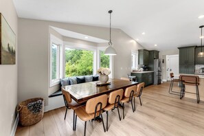 Eine moderne Küche mit Essbereich, großen Fenstern und Blick auf Grünflächen.