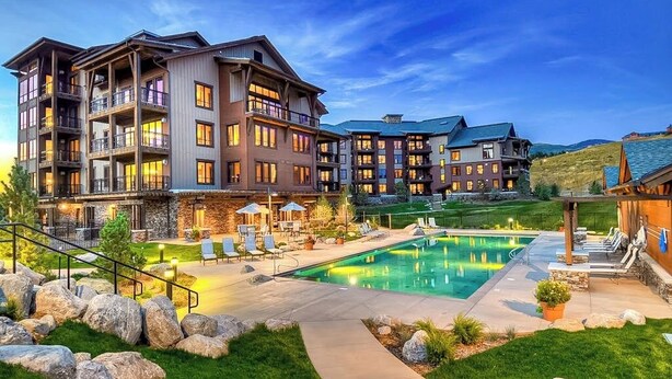 Ein mehrstöckiges Hotel mit Swimmingpool, Außenbereich und gepflegtem Rasen.