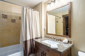 Ein Badezimmer mit Dusche, Waschbecken mit Spiegel und Toilette.