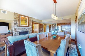 A spacious dining area with a long wooden table and cushioned seating. - Gorgeous posh condo w/shared pool, hot tubs, fitness, game room & more (Steamboat Springs)