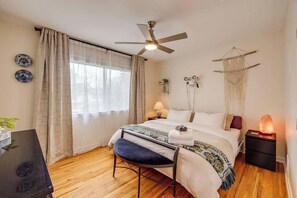 A bedroom with a bed, a desk, a chair, a heater, and a ceiling fan. - King Bed, AC, 75 min Banff, Newly Renovated (Calgary)