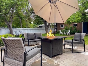 An outdoor patio with a square table, four chairs, and a large umbrella. - King Bed, AC, 75 min Banff, Newly Renovated (Calgary)