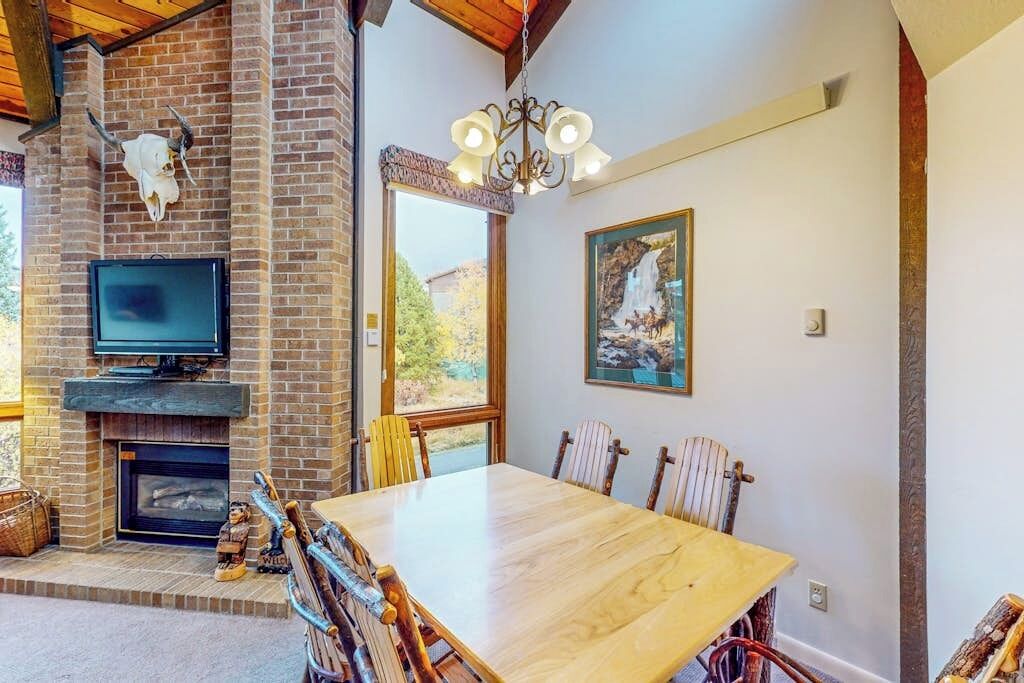 A dining area with a brick fireplace, a television, and a painting on the wall.