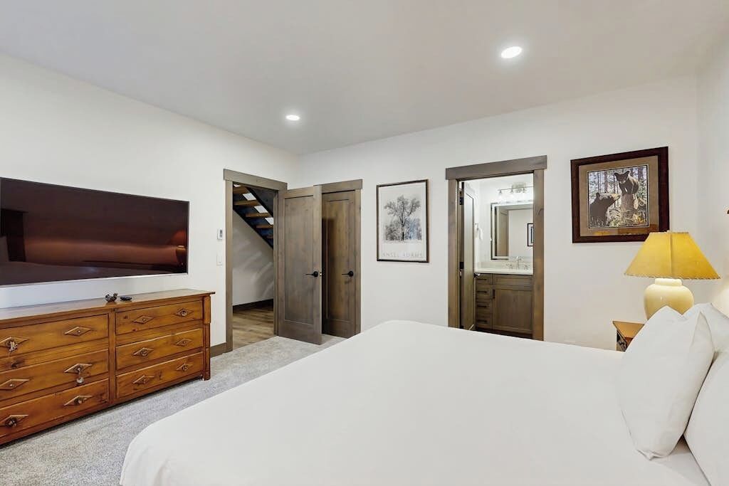 Een slaapkamer met een groot bed, een dressoir, een televisie en een lamp.