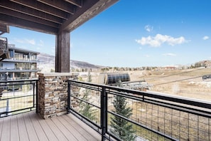 Ein Balkon mit Steinmauer, Holzdeck und Blick auf eine Berglandschaft.
