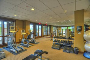 Ein Fitnessraum mit Laufbändern, Crosstrainern, Kurzhanteln und Gewichtbänken.