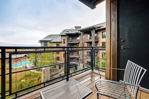 Ein Balkon mit Blick auf einen Pool und Gebäude, ein Stuhl und ein Tisch.