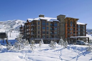 A multi-story hotel with balconies, a ski lift in the background, and a snowy landscape. - Impressive condo w/private balcony, gondola access, shared pool and hot tubs (Steamboat Springs)