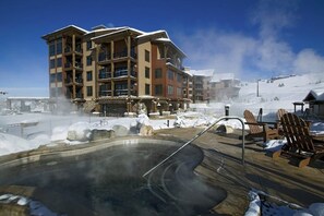 A multi-story building with balconies, a heated outdoor pool, and snow-covered surroundings. - Impressive condo w/private balcony, gondola access, shared pool and hot tubs (Steamboat Springs)