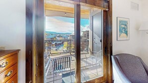 Ein Zimmer mit einer Schiebetür zu einem Balkon mit Blick auf Gebäude und einen Pool.