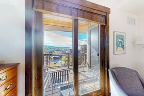 A room with a sliding glass door leading to a balcony with a view of buildings and a pool. - Perfect upscale studio w/private balcony, gondola access & shared hot tubs, pool (Steamboat Springs)