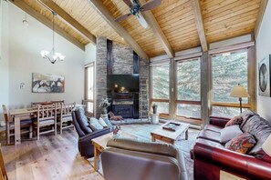 Ein geräumiges Wohnzimmer mit Kamin, Holzboden und großen Fenstern.