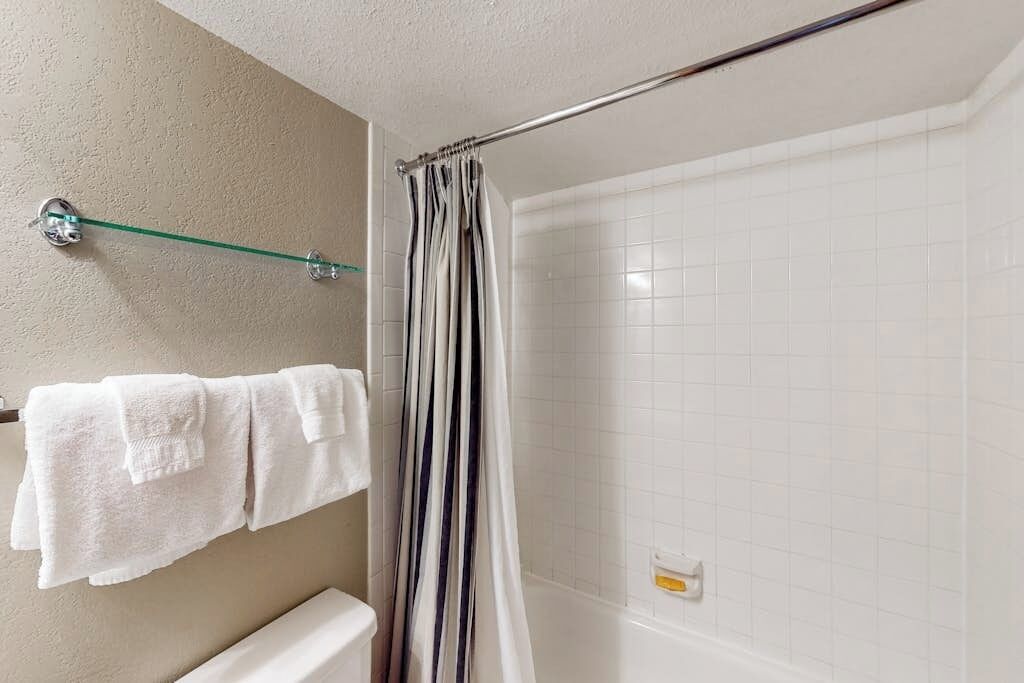 A bathroom with a shower, a glass towel rack, and a toilet.