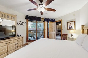 Ein Schlafzimmer mit einem Bett, einem Holzschrank, einem Deckenventilator und Blick ins Freie.