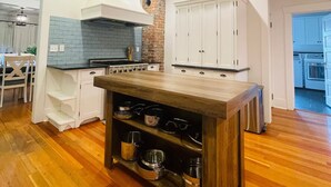A modern kitchen with white cabinetry, a wooden island, and a brick accent wall. - Lovely 4-bed/2-bath house with plenty of space for large groups (Moscow)