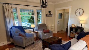 A living room with a sofa, armchairs, a coffee table, a rug, a clock, and a door leading to another room. - Lovely 4-bed/2-bath house with plenty of space for large groups (Moscow)