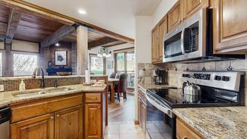 A kitchen with wooden cabinets, granite countertops, a stainless steel oven, and a large window.