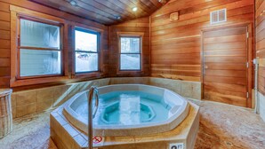 Een houten blokhut van binnen met een jacuzzi, twee ramen en een deur.