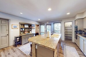 A spacious kitchen with a granite island, built-in shelving, and a view through the windows. - Large updated condo with full kitchen & private balcony - near resort trails (Steamboat Springs)