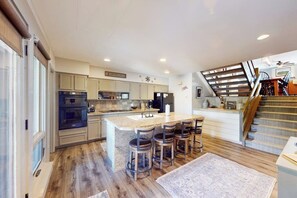 A kitchen with a central island, bar stools, and a staircase. - Large updated condo with full kitchen & private balcony - near resort trails (Steamboat Springs)