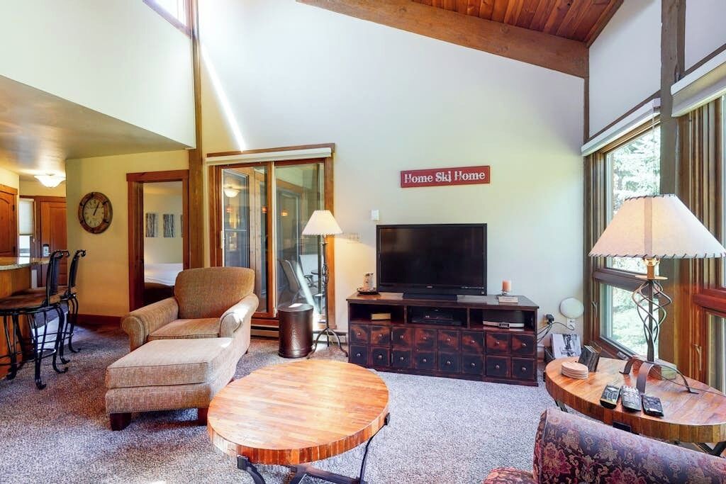 A cozy living room with a sofa, a coffee table, a TV, and a fireplace.