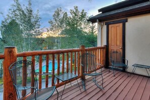 A wooden deck with metal chairs and a door. - Large family townhome with pool, hot tubs, tennis court, balcony, & deck (Steamboat Springs)
