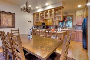 A dining area with a wooden table and chairs, wooden cabinets, and a chandelier. - Cross Timbers #2706 corner townhome with garage and primary suite balcony (Steamboat Springs)
