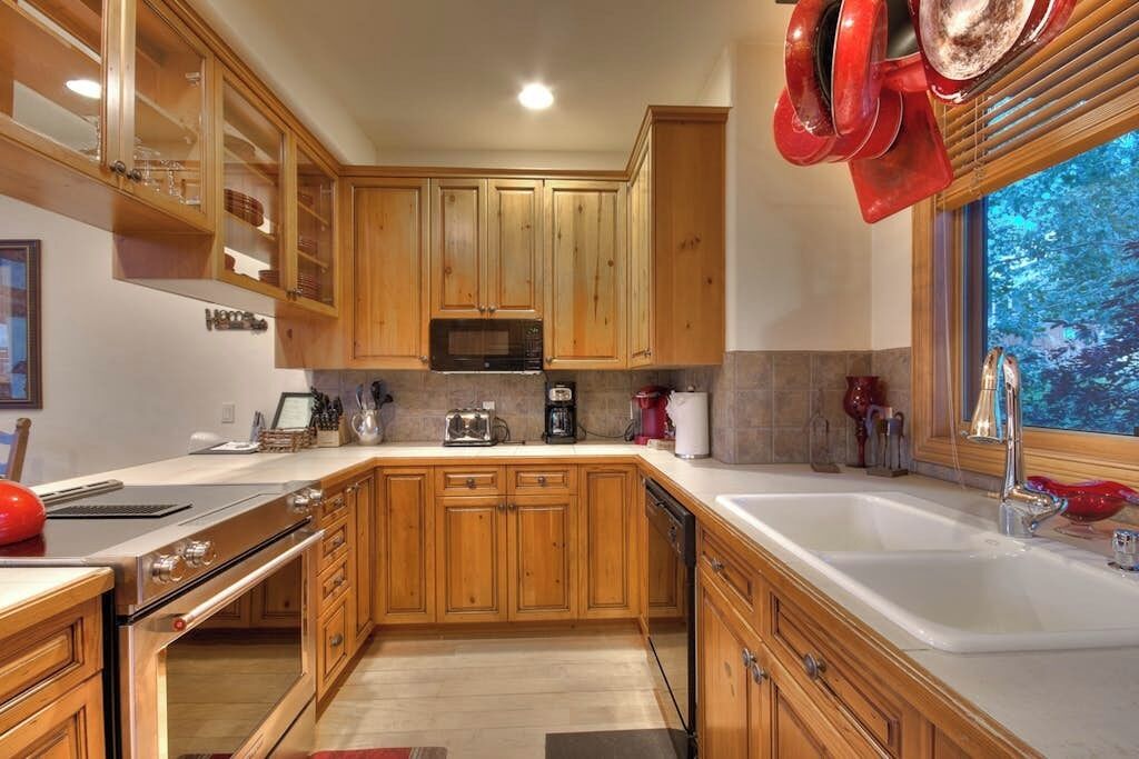 A kitchen with wooden cabinets, a stainless steel stove, a microwave, and a sink.