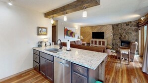 A kitchen with a granite countertop, stainless steel appliances, and a stone wall. - Intimate condo with fireplace, washer/dryer, outdoor pool & hot tub (Steamboat Springs)